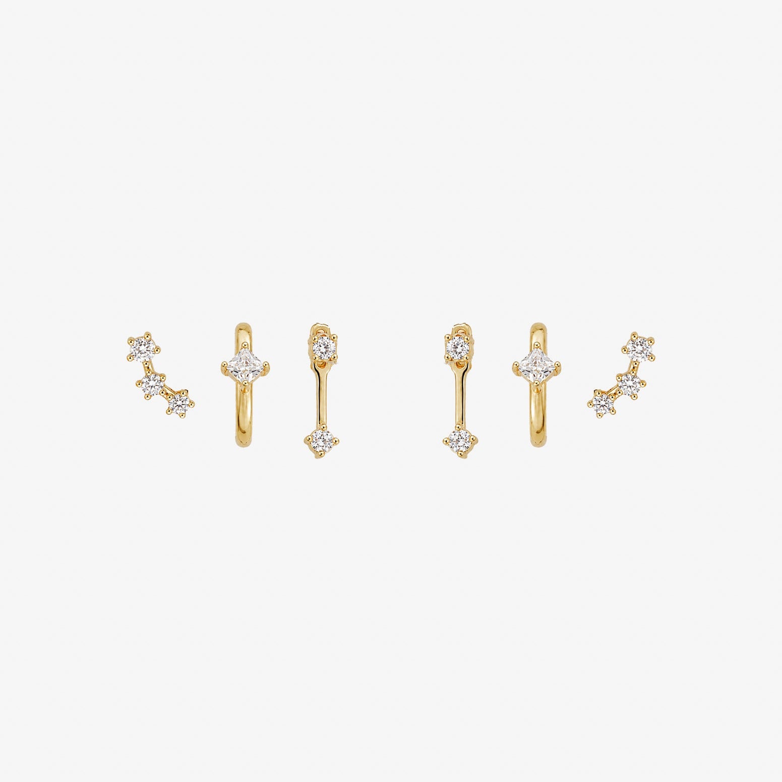 A set of three gold-toned ear cuff earrings with clear gemstones, arranged horizontally on a plain white background.