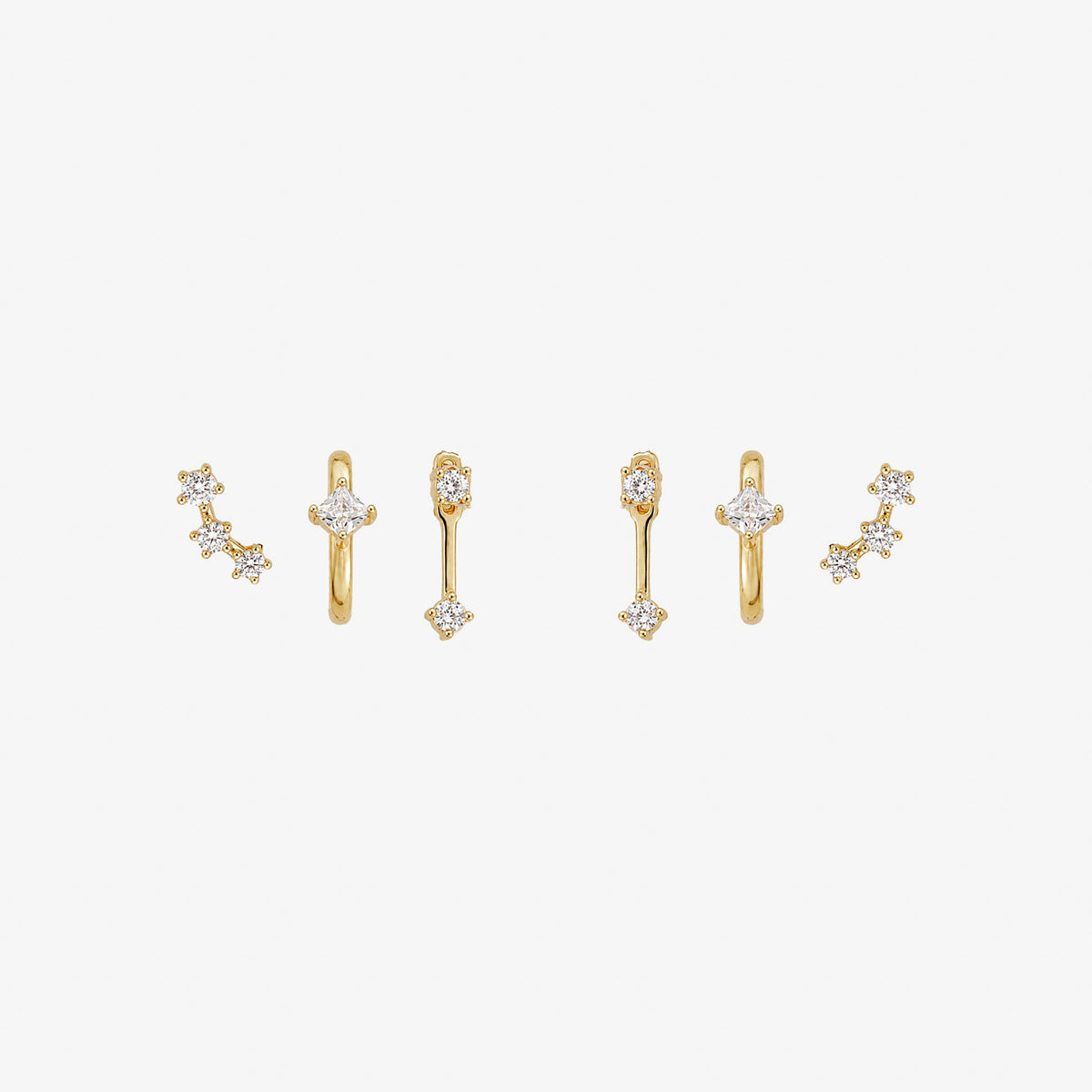 A set of three gold-toned ear cuff earrings with clear gemstones, arranged horizontally on a plain white background.